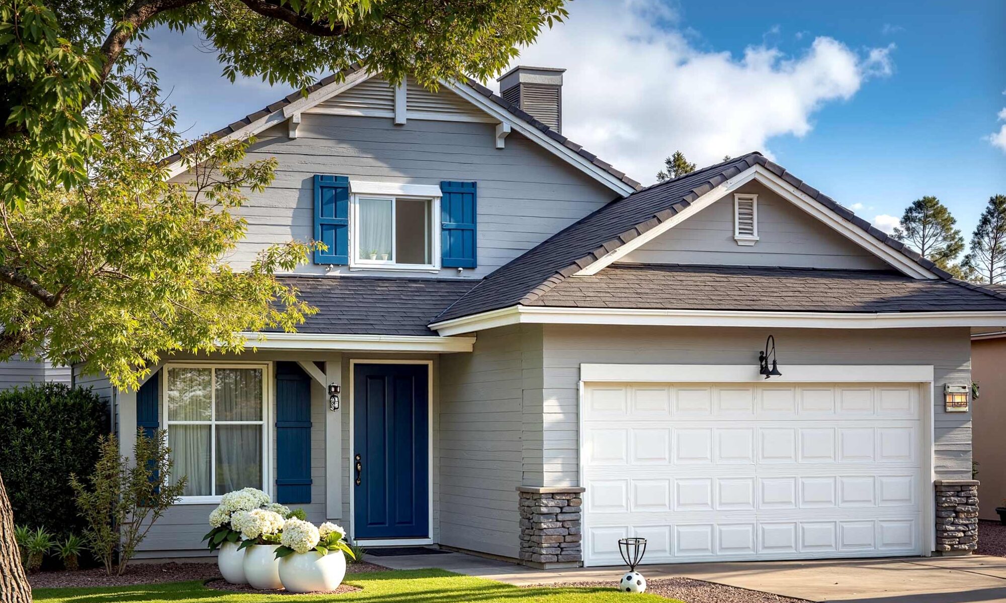Arcadia home with light gray siding and crisp white trim and navy-blue front door, classic light gray house with white trim navy door fresh paint and obvious peeling paint near window in scottsdale morning light, suburban house with light gray siding, white trim, and navy blue front door, freshly painted except for a clear area of peeling paint and wood rot beneath one front window. Two-car garage faces a dirty, stained driveway in a Scottsdale neighborhood. Lush landscaping, dynamic morning sunlight, and lived-in details complete the scene. Why does my house look dirty even after cleaning? Does my house need to be painted? , does my house need to be painted, does my home need repainting, should I repaint my house, is it time to repaint my house, time to repaint my home, when should I paint my house, how to know if house needs painting, exterior house painting, painting the outside of your house, exterior painting, house exterior painting, house painting outside, painting home exterior