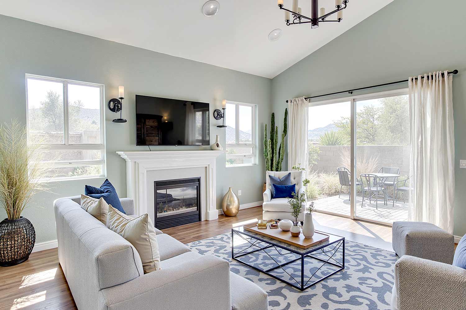 Arcadia living room with soft blue green walls and light oak floors and gray sectional, spacious modern living room with soft blue-green walls light oak flooring and a large light gray sectional sofa featuring textured pillows and sculptural poufs. Harsh late morning sunlight streams through sliding glass doors revealing a desert patio and mountain views in a Scottsdale neighborhood. The space feels fresh and serene with shiny trim and dynamic natural lighting. 2 coats of paint are better than 1 in house painting, Bryce House Painting, two coats of paint benefits, why two coats of paint are better, is two coats of paint necessary, painting with two coats vs one coat, best paint coverage with two coats, how many coats of paint do i need, two coats of paint for durability, professional painting two coats, painting tips two coats better, house painting two coats recommendation, interior painting two coats advantage, exterior painting two coats importance, two coats of paint for better finish, painting contractors recommend two coats, cost of two coats of paint vs one