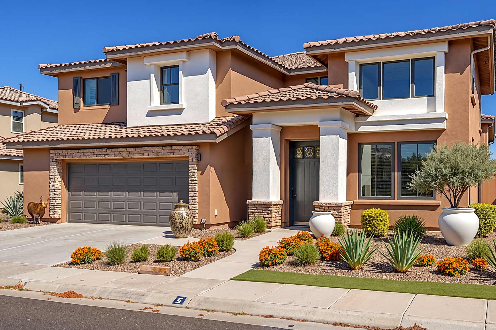 Large Mediterranean Revival house with a two-car garage in a Scottsdale neighborhood, recently painted with warm tan and crisp white walls, dark brown trim, and a gray garage door. Features lush landscaping, a modern bronze sculpture, and a dirty, stained driveway in dramatic late afternoon sunlight. terra cotta house, affordable exterior painting contractors, best exterior home painting contractors, Transform Your Home's Curb Appeal with one of the Best Exterior Painting Contractors in Phoenix, best exterior painting contractors, exterior painting contractor near me, exterior painting contractors near me, exterior paint contractor near me, exterior paint contractors near me, exterior painting company near me, exterior house painting contractors, exterior home painting contractors, exterior painting contractor, exterior painting contractors, exterior paint contractors, Phoenix, Scottsdale, Arcadia
