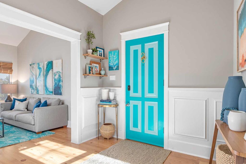 mid-century hallway with turquoise paneled door white insets and soft gray walls and white trim, mid century hallway with a turquoise paneled door and white insets soft gray walls and oak flooring in a Phoenix home featuring artistic décor and dramatic moody lighting, refresh interior doors, creative door painting, door color ideas, painted door inspiration, unique door painting designs, ideas for painting doors, painting indoor doors, painting doors inside, painting home interior doors, how to paint interior doors, home color palette