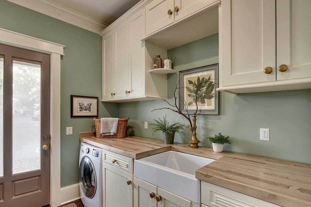 Charming English Cottage Laundry Room with Sage Walls and Creamy Off-White Cabinets-1, laundry room paint colors, laundry room color schemes, laundry room color palettes, paint colors for laundry rooms, best colors for laundry rooms, washroom paint colors, laundry space hues, laundry room paint shades