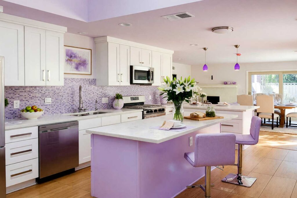 Soft Lavender Island in a Bright White and Pale Warm White Scottsdale Kitchen-3, a dreamy Scottsdale neighborhood kitchen with Shaker-style cabinets in bright white. A soft lavender island adds personality, accented by white lilies, green apples, and abstract artwork. Dynamic lighting enhances the room’s charm, island color combinations, kitchen island color inspiration, island paint colors, island color inspiration, contrasting island colors, bold island colors, accent island colors, kitchen island accent color, island accent color