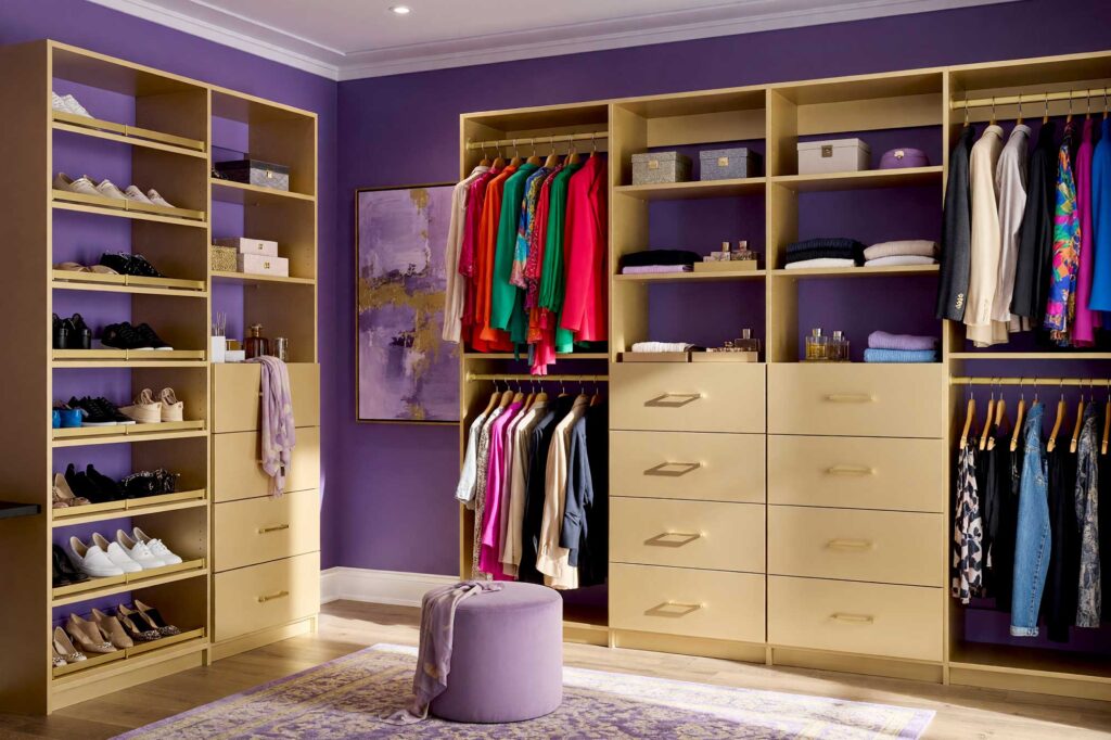 Walk-in Closet with Rich Amethyst Walls and Champagne Gold Cabinetry-2-FEATURE, vibrant walk-in closet with amethyst walls pale silver-lavender ceiling champagne gold cabinetry and warm hardwood floors Scottsdale neighborhood vibrant walk-in closet with amethyst walls pale silver-lavender ceiling champagne gold cabinetry and warm hardwood floors boutique dressing room feel in a Scottsdale neighborhood sunlight casting dramatic shadows luxurious and fresh design, walk-in closet paint ideas, closet color ideas, closet painting inspiration, walk-in closet color schemes, walk-in closet paint colors, walk-in wardrobe paint ideas, walk-in closet wall colors, walk-in wardrobe color schemes, dressing room color ideas, dressing room color schemes, dressing room wall colors