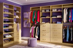 Walk-in Closet with Rich Amethyst Walls and Champagne Gold Cabinetry-2-FEATURE, vibrant walk-in closet with amethyst walls pale silver-lavender ceiling champagne gold cabinetry and warm hardwood floors Scottsdale neighborhood vibrant walk-in closet with amethyst walls pale silver-lavender ceiling champagne gold cabinetry and warm hardwood floors boutique dressing room feel in a Scottsdale neighborhood sunlight casting dramatic shadows luxurious and fresh design, walk-in closet paint ideas, closet color ideas, closet painting inspiration, walk-in closet color schemes, walk-in closet paint colors, walk-in wardrobe paint ideas, walk-in closet wall colors, walk-in wardrobe color schemes, dressing room color ideas, dressing room color schemes, dressing room wall colors