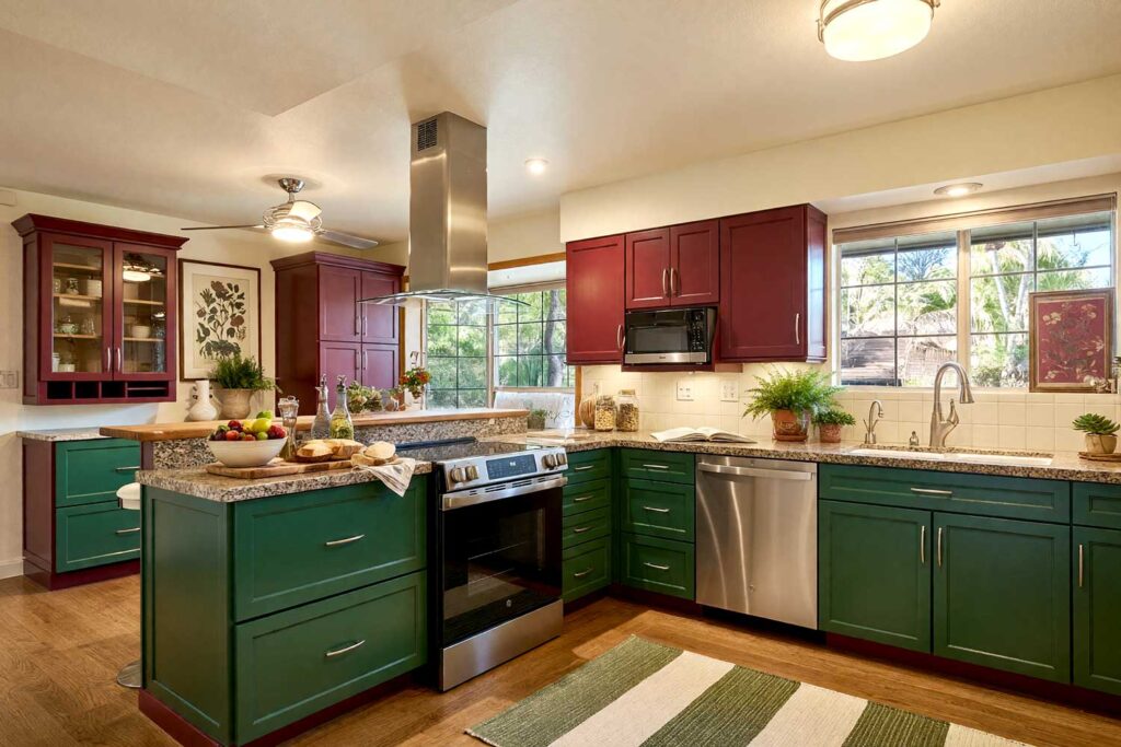 Kitchen with Cranberry Red and Deep Hunter Green Two-Toned Cabinets-3, a rich and striking scottsdale neighborhood kitchen with shaker-style cabinets. the upper cabinets are painted in cranberry red, while the lower cabinets are deep hunter green. the space features warm cream walls, antique ivory trim, and natural oak flooring. décor includes a wooden cutting board, ceramic fruit bowl, potted plants, and botanical artwork. dramatic sunlight and moody lighting enhance the fresh and inviting atmosphere, two-tone kitchen cabinets, dual-tone kitchen cabinets, two-color kitchen cabinets, contrasting kitchen cabinets, multi-colored kitchen cabinets
