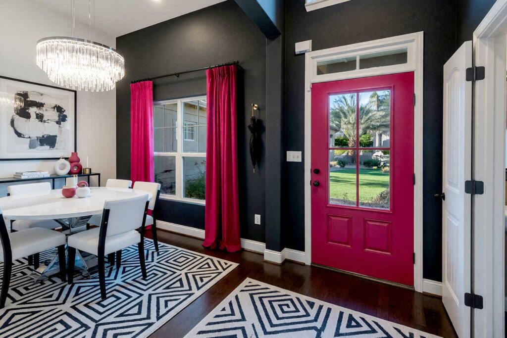 Minimalist Provocateur Foyer with Graphite Charcoal Walls and Cerise Door-2, minimalist provocateur foyer featuring graphite charcoal walls bold cerise door matte white trim and soft pale gray ceiling in a freshly painted Scottsdale neighborhood home. sleek modern decor includes black metal console table abstract art geometric rug and brass accents illuminated by strong midday sunlight casting sharp shadows and bright highlights for a dramatic and contemporary entrance, bold foyer paint colors, foyer paint color ideas, entryway paint colors, bold interior color choices, interior color choices, dark entryway colors, dark foyer colors, dark tones, moody entryway