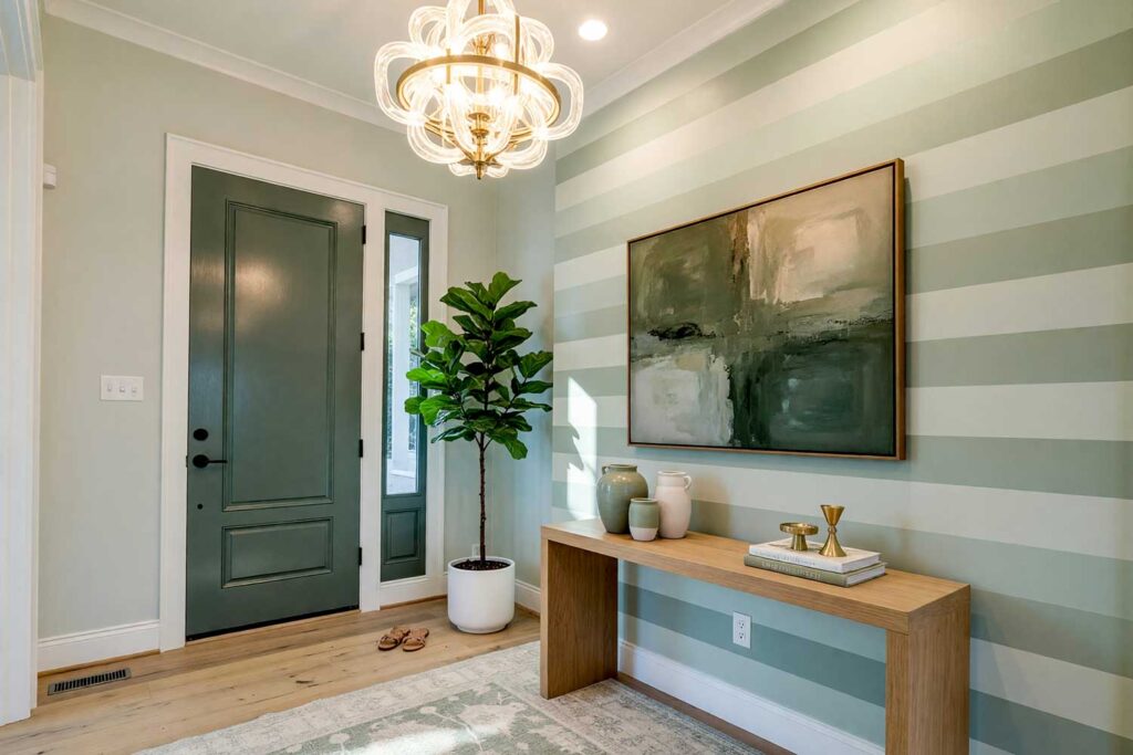 Refined Minimalist Foyer with Light Sage Walls and Tone-on-Tone Stripes-7, refined minimalist foyer featuring light sage walls tone-on-tone sage stripes deep eucalyptus door and crisp warm white trim in a freshly painted Scottsdale neighborhood home. subtle decor includes natural wood console ceramic vases brass candleholder and a woven area rug illuminated by strong morning sunlight casting sharp shadows and bright highlights for a sophisticated and serene entrance, foyer paint colors, entryway paint schemes, entry hall paint colors, foyer colors, interior foyer paint colors, dramatic foyer paint colors