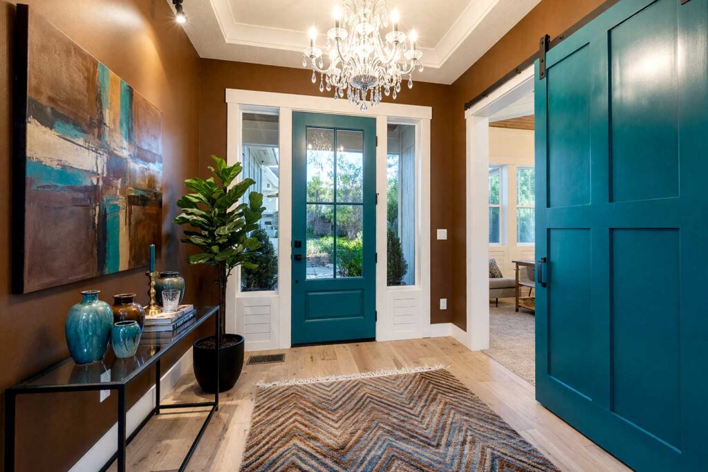 Unexpected Pairing Foyer with Tobacco Brown Walls and Electric Teal Doors-1, unexpected pairing foyer featuring warm tobacco brown walls vivid electric teal door bright white trim and pale sand ceiling in a freshly painted Scottsdale neighborhood home. bold decor includes black metal console table teal and brown ceramic vases brass candleholder and a plush area rug illuminated by strong morning sunlight casting sharp shadows and bright highlights for a vibrant and energetic entrance, foyer paint colors, entryway paint schemes, entry hall paint colors, foyer colors, interior foyer paint colors, dramatic foyer paint colors