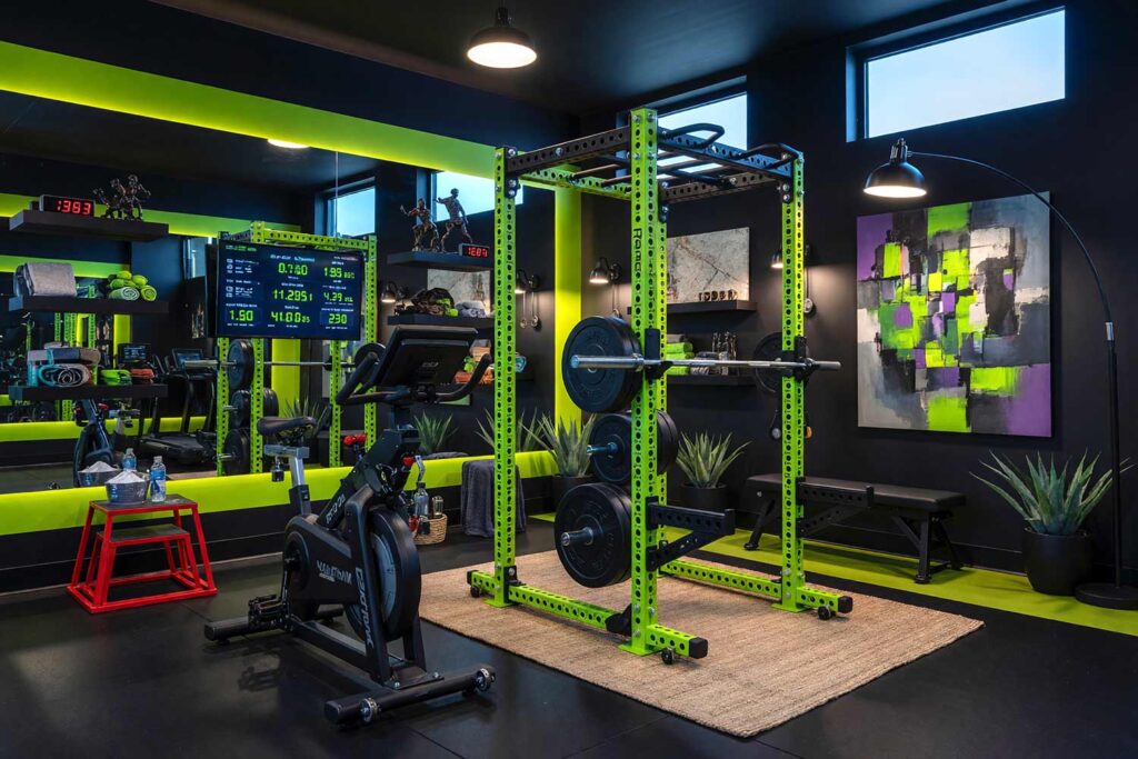 High-Tech Pain Cave with Deep Charcoal Walls Neon Lime Accent and Matte Black Trim-9, high-tech home gym paint colors deep charcoal walls neon lime green accent slash matte black trim rubber flooring power rack interval training scottsdale. A high-tech futuristic pain cave in a Scottsdale neighborhood featuring a Rogue Fitness Monster Series Power Rack positioned against a dramatic neon lime green accent slash, surrounded by deep charcoal walls that swallow light and create an aggressive, immersive atmosphere. Curated high-tech décor includes a Concept2 RowErg, NordicTrack Commercial S22i Studio Cycle, a wall-mounted screen displaying real-time metrics in neon green text, a bHaptics TactSuit Pro haptic feedback vest, and smart color-changing bulbs synchronized with a wall-mounted sound system. Premium rubber matting with an ozone and fresh rubber scent grounds the space in industrial sophistication, while matte black trim and LED-backlit mirrors amplify the high-tech aesthetic. Dramatic natural light and color-changing smart bulbs pulse and bounce against the charcoal and matte black surfaces, creating a nightclub-like atmosphere that transforms every interval session into an immersive, aggressive training experience where suffering is the goal and every number beaten is a victory. home gym paint colors, gym paint colors, workout room color, home gym color palette, home gym color scheme, workout space paint colors, exercise room paint colors