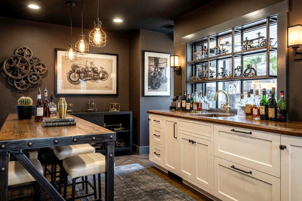Industrial Loft Home Bar with Espresso Brown Walls and Ivory Cabinets-4, moody industrial loft home bar espresso brown walls ivory cabinets matte black ceiling light charcoal gray baseboards. A dramatic home bar in a Scottsdale neighborhood featuring a blackened steel bar, ivory leather stools, and Edison-style lighting. Décor includes vintage blueprints, open shelving with crystal decanters, and industrial-inspired accessories. Dramatic natural and artificial light highlights the bold textures and moody palette of this urban loft-inspired space. bar cabinet paint colors, home bar color palette, wine nook paint colors, built-in bar paint scheme, bar area color combinations