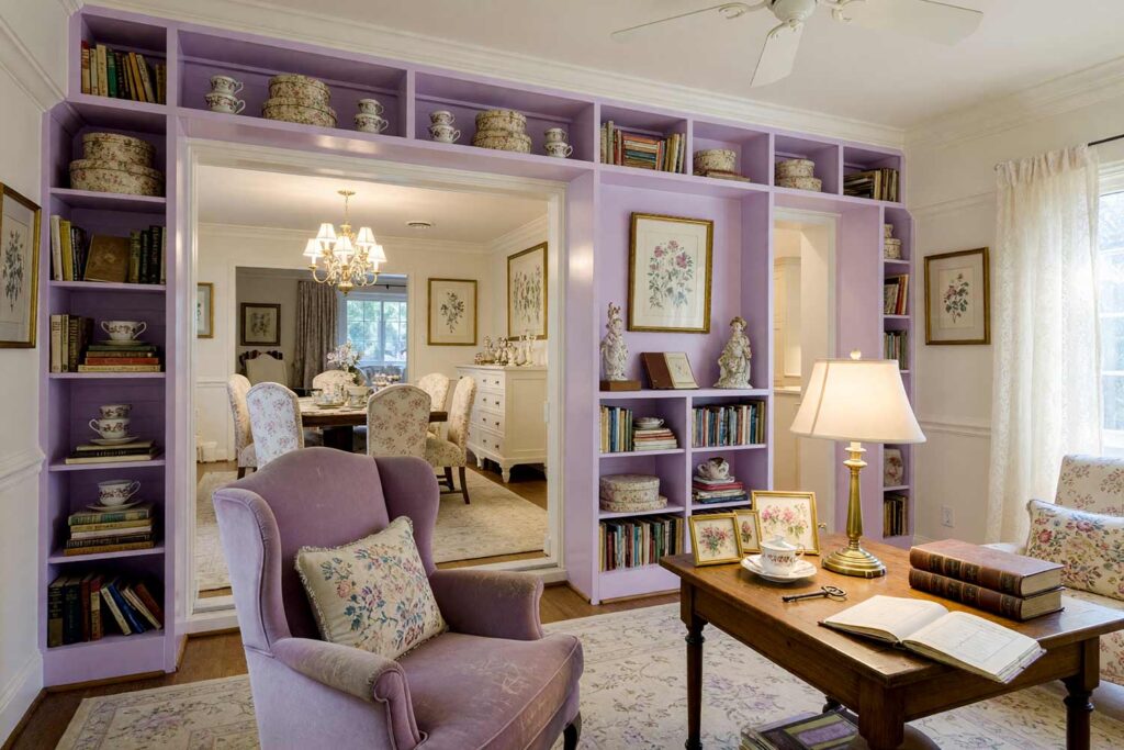 Lavender British Countryside Estate Library with Dove White Trim and Pale Oat Walls-7, soft lavender british countryside estate library dove white trim pale oat walls and ceiling. A refined library in a Scottsdale neighborhood featuring soft lavender built-in bookshelves against pale oat walls with dove white trim. Grandmillennial décor includes needlepoint pillows, chintz-covered hatboxes, antique teacups, and pressed botanical prints. Soft morning sunlight enhances the inherited, timeless atmosphere, offering elegant bookshelf paint color ideas for painting built-in bookshelves with gentle countryside charm. paint colors for built-in shelving, built-in cabinetry paint ideas, bookshelf color palette ideas, painted bookcase design inspiration, colors for built-in bookshelves, bookshelf and cabinet paint pairings