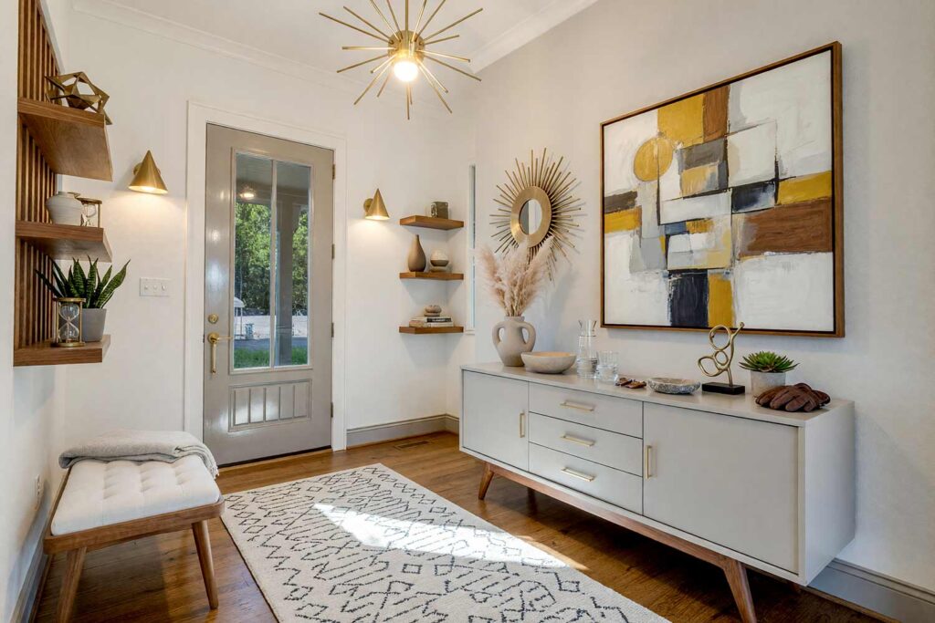 Mid-Century Modern Entryway with Warm White Walls and Deep Charcoal Console-2, mid century modern entryway neutral interior paint colors warm white walls charcoal accent wall charcoal trim walnut flooring. A striking foyer in a Scottsdale neighborhood featuring a deep charcoal console with sculptural legs, brass sputnik pendant lighting, starburst mirror, and walnut hardwood floors. Outfitted with a cubist architecture artwork, ceramic catch-all bowl, and geometric runner rug. High-contrast directional daylight creates dramatic highlights and deep shadows. neutral tones for interiors, neutral wall paint colors, muted neutral colors, soft neutral color palette, interior neutral color palette