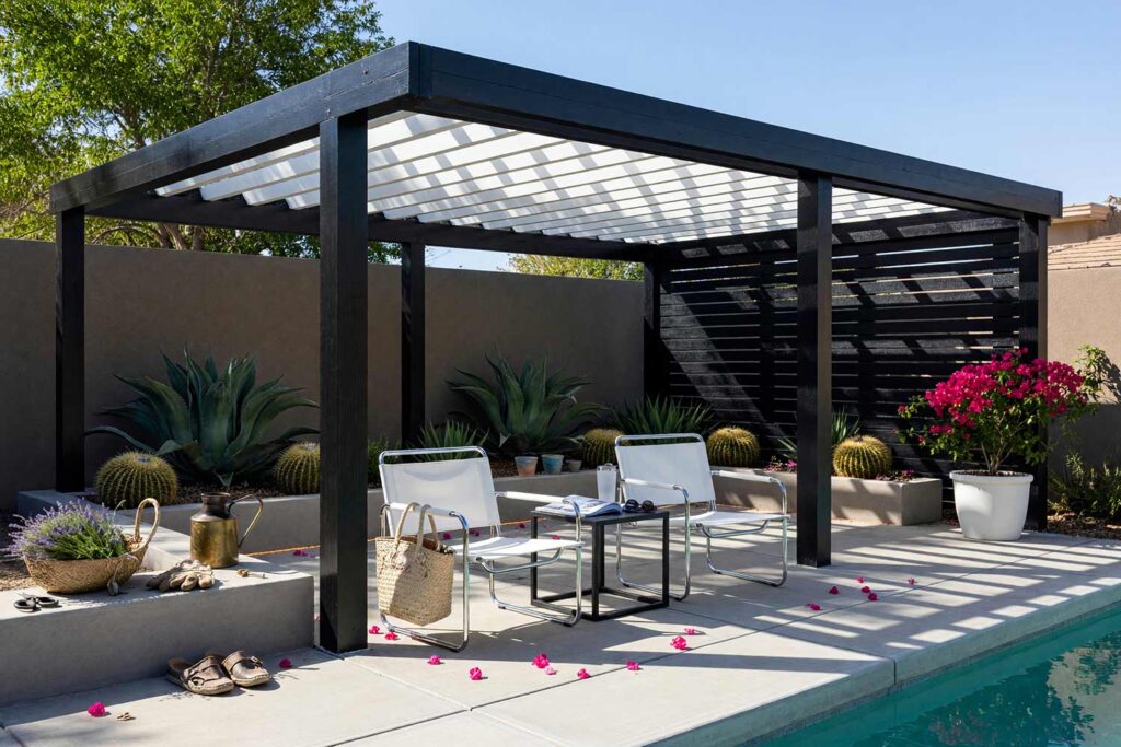 Bauhaus Pergola with Crisp Black Framing and Bright White Overhead Slats-6, bauhaus pergola crisp black posts bright white slats trellis screen pergola paint colors. Located at a custom Scottsdale home, this architectural pavilion pairs semi-gloss crisp black posts with bright white roof slats and a modern privacy screen. Tubular steel lounge chairs and poured concrete ground the space, while dramatic late-afternoon sunlight casts vivid geometric shadows across the patio deck. pergola paint colors, painted pergola ideas, painting an outdoor pergola, painting backyard ramada, pergola color ideas, pergola color schemes, what color to paint a pergola