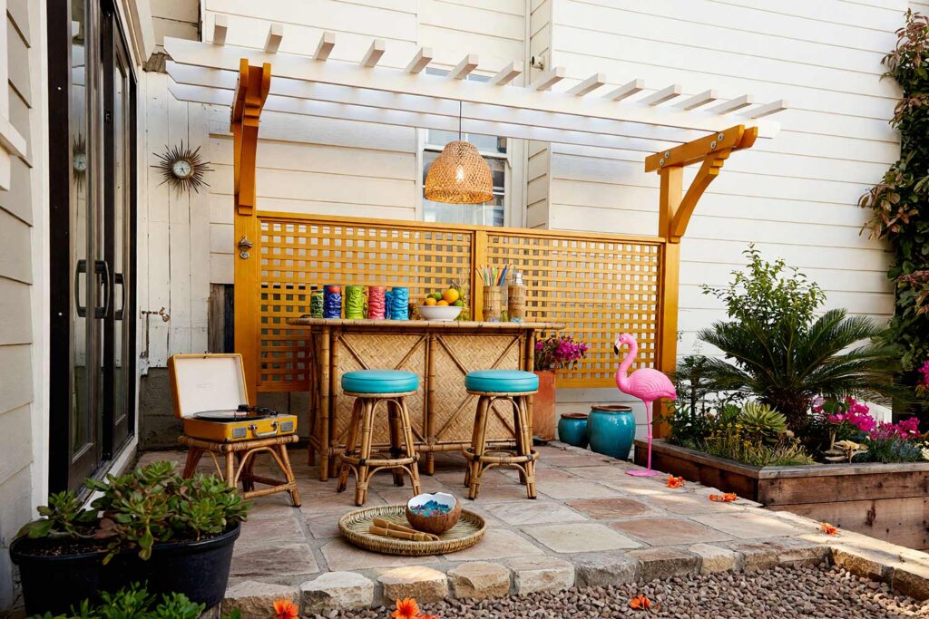 Retro Tiki Lounge Pergola with Golden Ochre Framing and Cloud White Slats-4, retro tiki lounge pergola golden ochre posts cloud white slats trellis pergola paint colors. Located at a custom Scottsdale property, this retro tiki pergola pairs semi-gloss golden ochre posts with crisp cloud white roof slats and an ochre trellis screen. Flagstone pavers, a bamboo bar, ceramic tiki mugs, and glowing pendant lighting create an energetic sunset escape under dramatic golden-hour shadows. painting a cedar pergola, ramada paint colors, trellis paint colors, backyard shade structure colors, best paint for an outdoor pergola
