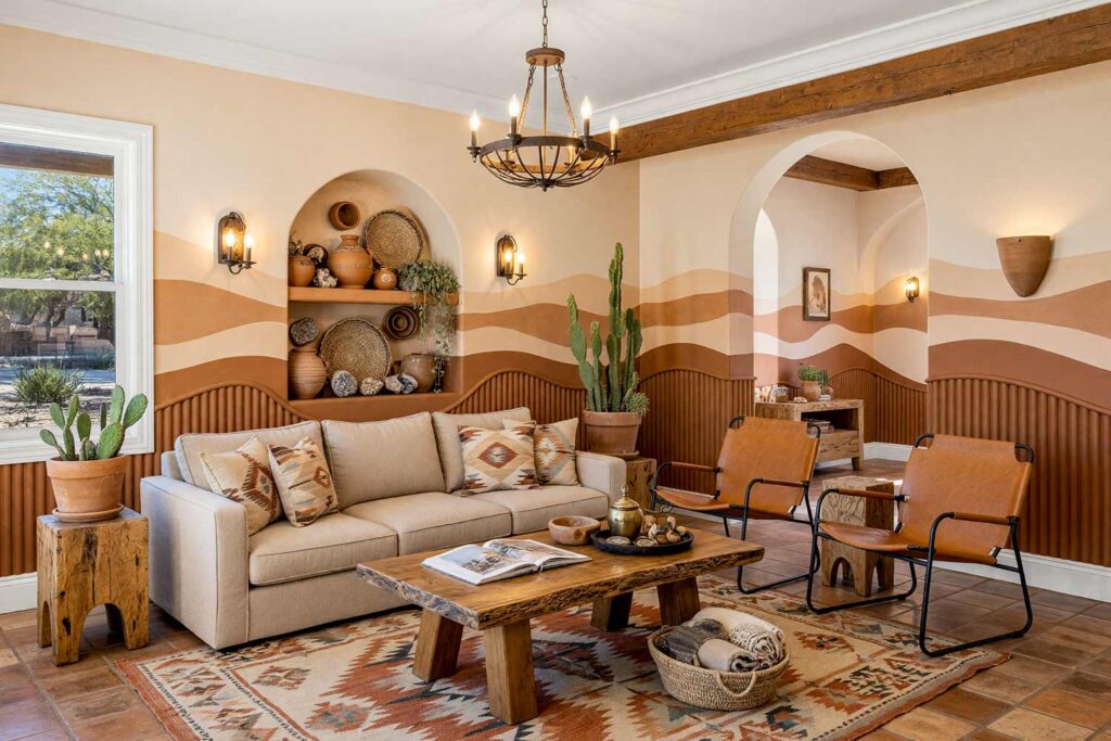 Southwestern Living Room with Cream Walls and Clay Terracotta Wave Bands with Fluted Tambour Slatting-4, southwestern living room adobe cream walls clay terracotta wave bands fluted tambour slatting sandstone white baseboards saltillo tile floors painting creative wall treatments. A sun-drenched desert oasis in a Scottsdale neighborhood featuring an oat linen sofa, saltillo tile floors, a live-edge mesquite coffee table, and an accent wall of painted terracotta wave bands faced with fluted tambour slatting. Direct sunlight streams through casement windows, casting dramatic linear shadows across the fluted wood and accentuating the glossy sandstone white trim. painting creative wall treatments, creative wall treatments, mixed material wall treatments, dimensional painted walls, textured accent wall ideas, metal accent wall ideas