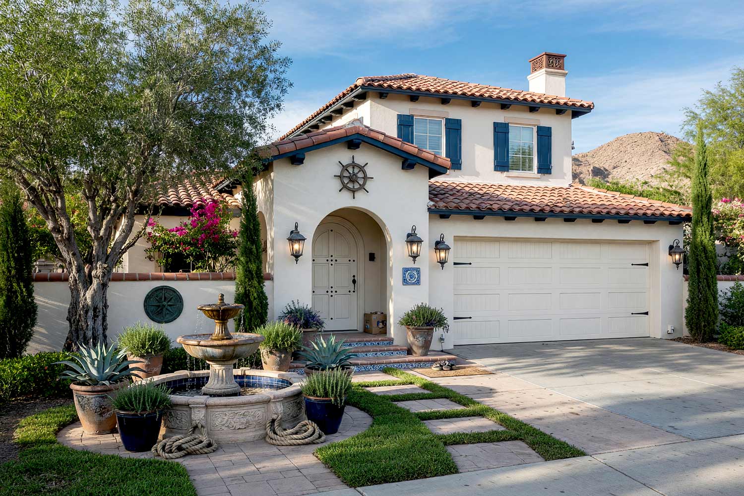 Spanish Revival Home with White Stucco and Harbor Navy Shutters-7, spanish revival exterior paint colors oyster white stucco harbor navy shutters jet black lanterns concrete driveway front facade. A custom estate in a Scottsdale neighborhood featuring freshly painted stucco, glossy hand-finished trim, and elevated exterior painting curb appeal. Shiny semi-gloss harbor navy shutters and a garden gate accent crisp oyster white walls under faded brick-red terracotta roof tiles. An asymmetrical Cantera stone fountain, maritime loggia artwork, and mature olive trees complete the luxury coastal design under dynamic golden hour illumination. spanish revival exterior paint colors, spanish style house paint colors, santa barbara exterior colors, modern mediterranean house paint, spanish colonial revival exterior colors