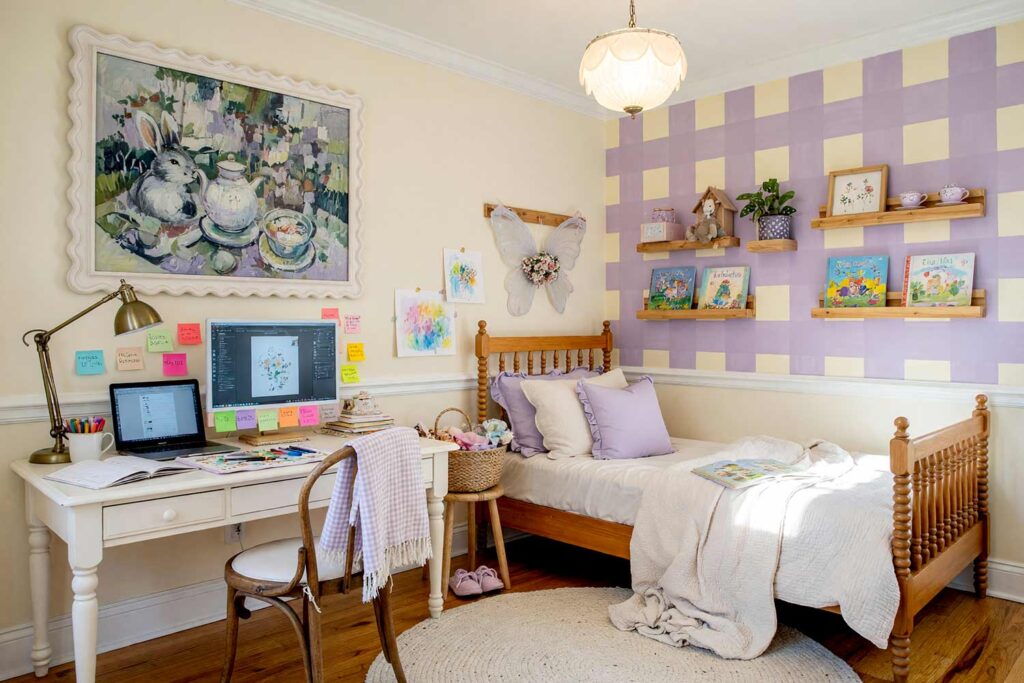 Whimsical Child’s Bedroom with Light Buttermilk and Dusty Lilac Graphic-10, kid’s bedroom paint colors cottagecore light buttermilk dusty lilac white chair rail pine floor. An imaginative Cottagecore child's bedroom in a Scottsdale neighborhood featuring light buttermilk walls, an artisan painted gingham check panel in dusty lilac and buttermilk, and glossy white semi-gloss trim and chair rail molding. The multi-functional kid's space unites an inviting unmade wooden spindle bed with an active homework desk hosting a dual-screen computer setup, storybooks, charming crafts, and floating display ledges above the headboard. Rich honey pine flooring and striking, high-contrast sunlight evoke a sweet, storybook tea party atmosphere built for academic focus and childhood daydreaming. kid's bedroom paint colors, kids room color scheme, children's bedroom colors, kids bedroom color ideas, children's room paint colors