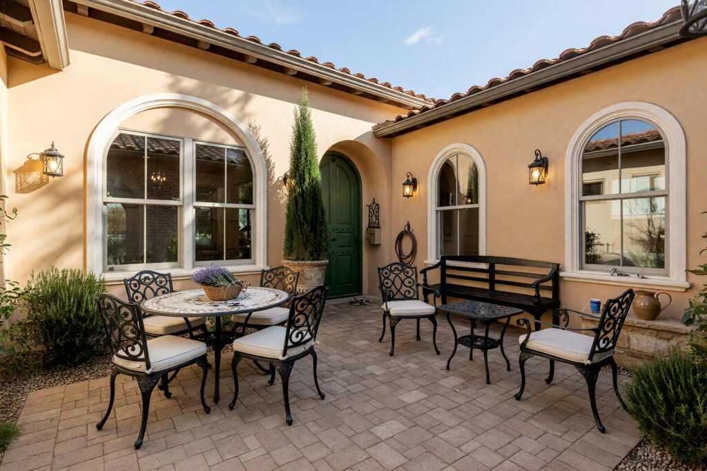Colonial Revival Courtyard with Warm Camel Stucco and White Archways and Green Door-7, spanish colonial revival exterior courtyard paint colors warm camel stucco bone white arch hunter green door. Set in a prestigious Scottsdale neighborhood, this entry sanctuary pairs matte warm camel plaster with a semi-gloss hunter green door and soft black iron gate. Accented by bone white arches, an Italian cypress urn, and dramatic golden-hour shadows. exterior courtyard paint colors, painting outdoor courtyard, enclosed courtyard color schemes, front courtyard painting ideas, front courtyard color ideas, courtyard wall paint colors