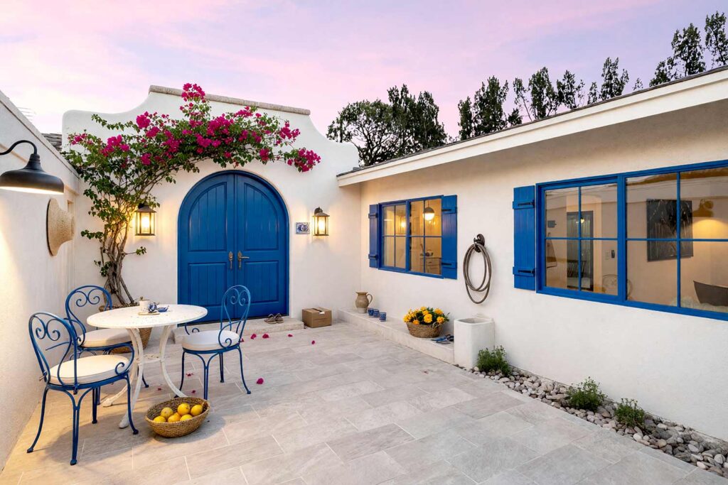 Mediterranean Courtyard with White Walls and Pale Stone Gray Caps and Cobalt Blue Door-6, aegean mediterranean exterior courtyard paint colors whitewash white walls pale stone gray cap cobalt blue door. This custom Scottsdale entry sanctuary pairs matte whitewash white plaster with a semi-gloss cobalt blue door and pale stone gray wall caps. Accented with climbing bougainvillea, a basket of lemons, and high-contrast late-afternoon golden hour shadows. entry courtyard paint colors, courtyard stucco paint colors, courtyard door color ideas, walled courtyard color schemes, outdoor courtyard color palette