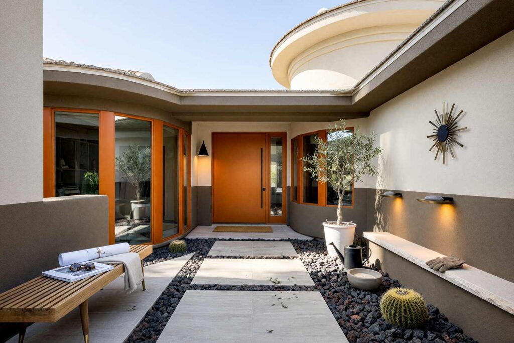 Mid-Century Modern Courtyard with Two-Tone Deep Taupe and Linen Walls with Orange Door-1, mid-century modern exterior courtyard paint colors deep taupe pale linen walls burnt orange door. This custom Scottsdale entry sanctuary pairs matte two-tone deep taupe and pale linen stucco with a semi-gloss burnt orange door and chalk white coping. Staged with a tapered-leg bench, starburst plaque, and dramatic late-afternoon golden hour shadows. entry courtyard paint colors, courtyard stucco paint colors, courtyard door color ideas, walled courtyard color schemes, outdoor courtyard color palette