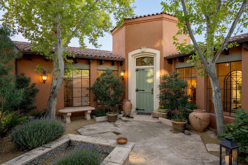 Tuscan Villa Courtyard with Terracotta Stucco Cream Arch Trim and Sage Green Entry-3, tuscan villa exterior courtyard paint colors terracotta walls cream archway trim sage green door. This custom Scottsdale entry sanctuary pairs matte mineral terracotta stucco with a semi-gloss sage green door and cream arch trim. Accented with potted olive trees, a cast-stone bench, and ceramic urns under rich golden-hour sunlight. entry courtyard paint colors, courtyard stucco paint colors, courtyard door color ideas, walled courtyard color schemes, outdoor courtyard color palette